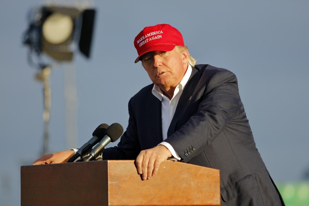SAN PEDRO, CA - SEPTEMBER 15, 2015: Donald Trump, 2016 Republican presidential candidate, speaks during a rally aboard the Battleship USS Iowa in San Pedro, Los Angeles, California while wearing a red baseball hat that says campaign slogan
