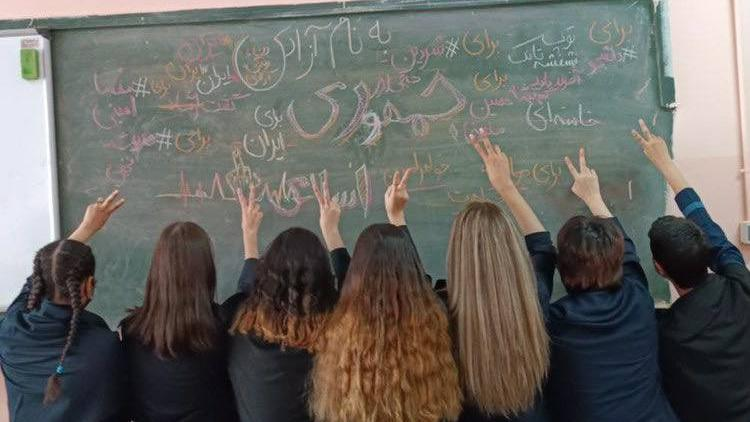 Schoolgirls without head coverings hold a classroom demonstration against Iranian leadership.